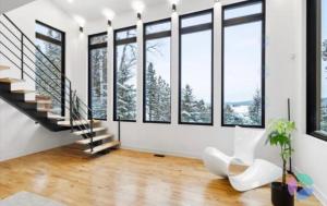 a living room with a staircase and large windows at Chalet ouareau in Saint-Donat-de-Montcalm