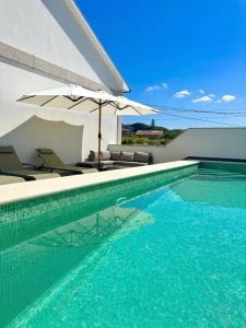 a swimming pool with an umbrella and chairs at Balcón da Ría in Cambados