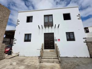 a white building with a black door and stairs at Casona IROKO in La Costa