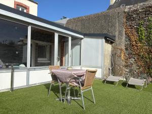 a patio with a table and chairs on the grass at Appart Résidence Yadah RDC in Granville