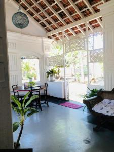 a living room with a table and chairs and windows at Casa Del Ceylon in Hikkaduwa