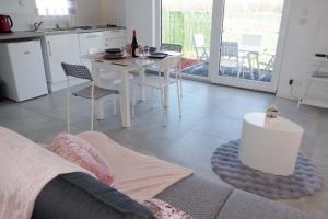 a living room with a white table and a kitchen at Grand studio La Sensée - Parking privé, Terrasse, Netflix, au calme in Hem-Lenglet
