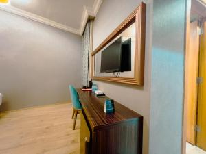 a room with a desk with a tv on a wall at فندق أوركيد مكة in Mecca