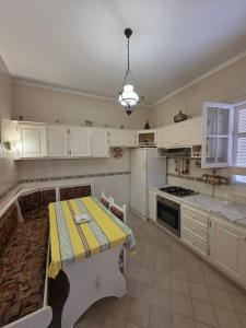 a kitchen with white cabinets and a table in it at Antique seaside appartement in Mahdia