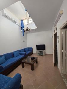 a living room with a blue couch and a tv at Antique seaside appartement in Mahdia
