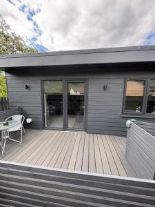 a house with a wooden deck with a table on it at Hillview Cabin in Oban