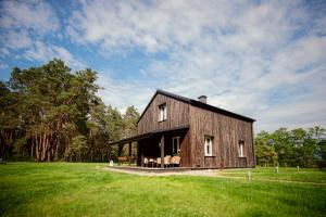 a large wooden barn in a grassy field at Dom pod Niebem in Lucimia