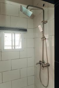 a shower in a white tiled bathroom with a window at Muster Point Hotel & Suites in Port Harcourt