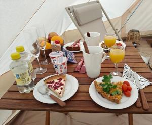 a wooden table with plates of food and drinks at Glamping Arctic Ukuli in Rovaniemi