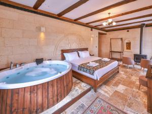 a bedroom with a large tub and a bed at Noble Crown Stone House Cappadocia in Uçhisar +84 photos