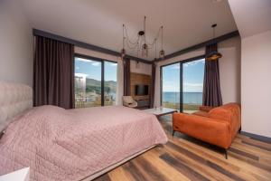 a bedroom with a bed and a chair and large windows at Boreti Panorama Residence in Boreti