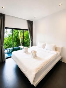 two teddy bears sitting on a bed in a bedroom at Villa Ravenala in Chaweng in Ban Ko Khwan