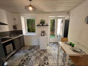 a room with a kitchen with a refrigerator and a table at Escapade en Auvergne - centre historique - 3 personnes in Olliergues