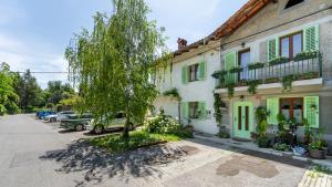 a tree in front of a building with cars parked at Hiša pri poetu in Šempeter pri Gorici