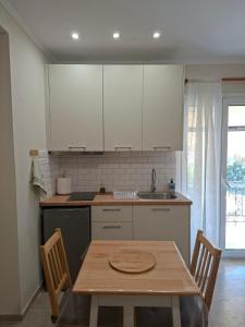 a kitchen with white cabinets and a table with chairs at Elia Studios 2 in Nydri