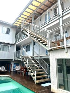 a building with a staircase next to a swimming pool at Pousada Caravela in Arraial do Cabo