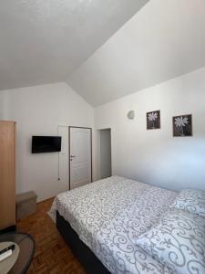 a white bedroom with a bed and a tv at Apartmani MM Trebinje in Trebinje