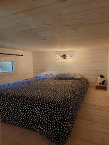 a bedroom with a bed with a black and white comforter at Tiny House L'esquirou in Pourrières