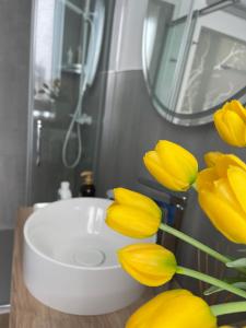 a bathroom with a white sink and yellow flowers at In Blu Santo Ospedale in Padova