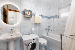 a bathroom with a sink and a washing machine at Apartman Izi Green s pogledom na more in Kornić