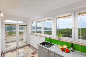 a kitchen with windows and a counter with a bowl of fruit at Apartman Izi Green s pogledom na more in Kornić +19 photos