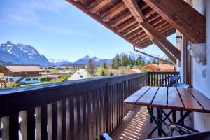 a wooden table on a balcony with a view of the mountains at Alpenhof Wallgau in Wallgau