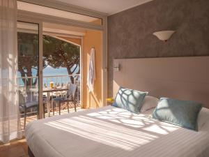 a bedroom with a bed and a balcony with a table at Hotel de la Plage in Le Lavandou