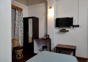 a bedroom with a bed and a tv on the wall at Crossroad in Shillong