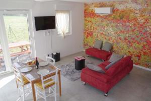 a living room with a red couch and a table at Les Coquelicots - Parking privé, Terrasse, Clim, Netflix, Au Calme in Hem-Lenglet