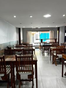 a restaurant with wooden tables and chairs and a piano at Pousada Caravela in Arraial do Cabo