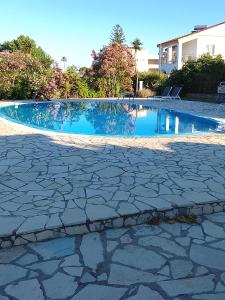 a swimming pool with a stone walkway around it at Sailor's Apartments Kavos in Kavos