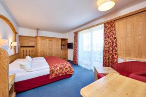 a hotel room with a bed and a red couch at Alpenhof Wallgau in Wallgau