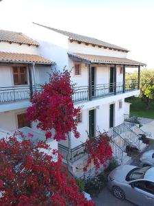 a white building with red flowers in front of it at Sailor's Apartments Kavos in Kavos