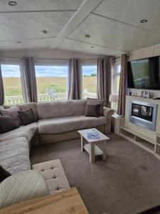 a living room with a couch and a tv at Riley's Caravan sand le mere tunstall view in Tunstall
