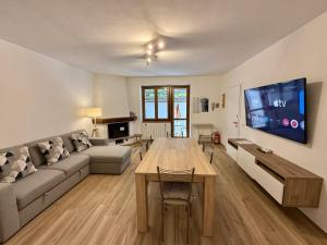 a living room with a couch and a table and a tv at Dolce Vetta Valmalenco in Chiesa in Valmalenco