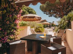 a patio with a table and chairs and umbrellas at Hotel de la Plage in Le Lavandou