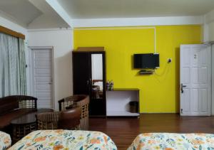 a room with a yellow wall with chairs and a tv at Crossroad in Shillong +43 photos