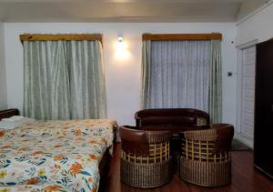 a bedroom with two chairs and a bed and curtains at Crossroad in Shillong