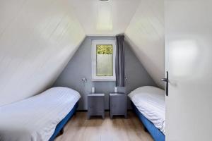 two beds in a small room with a window at Vijverzicht de Goudkarper 154 in Gramsbergen