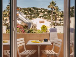 a balcony with a table and chairs and a view of a city at Hotel de la Plage in Le Lavandou