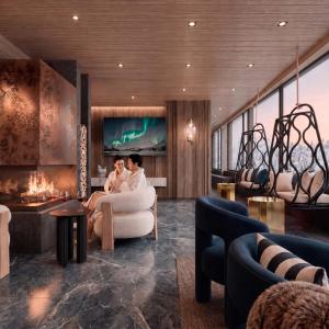two people sitting in a living room with a fireplace at SkyView Igloo Resort & Spa in Rovaniemi