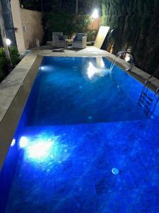 a swimming pool at night with blue lighting at Villa ghmate in El Kriet