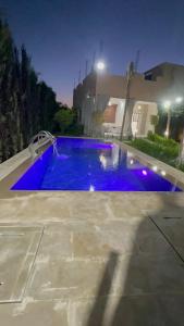 a large blue swimming pool in a yard at night at Villa ghmate in El Kriet