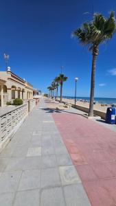 a sidewalk next to the beach with palm trees at Miramar Playa in La Playa de la Torre de Piles