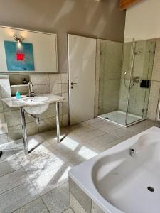 a bathroom with a tub and a sink and a shower at PaderCityLoft- lichtdurchflutet und privat mit Kamin-Dachterrasse-Sauna-Außendusche im Atrium in Paderborn
