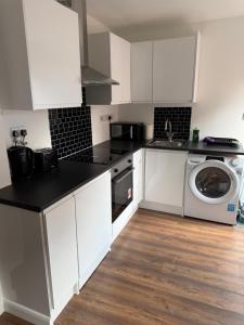 a kitchen with white cabinets and a washer and dryer at Stylish and Modern Space in Shenley Brook End