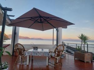 ein Tisch und Stühle unter einem Sonnenschirm auf einer Terrasse in der Unterkunft Albergo Seaside in Leni + 38 Fotos