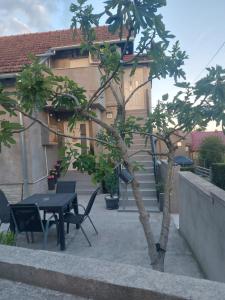 a small tree with a table and chairs in front of a building at Apartman Kovačić in Kutina