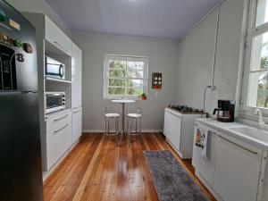 a kitchen with white cabinets and a wooden floor at Casa Finger próx do Centro e do Núcleo de Casas Enxaimel ambiente familiar in Ivoti