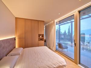 a bedroom with a bed and a large window at Luxury Apartments La Baia - Penthouse in Torri del Benaco +21 photos